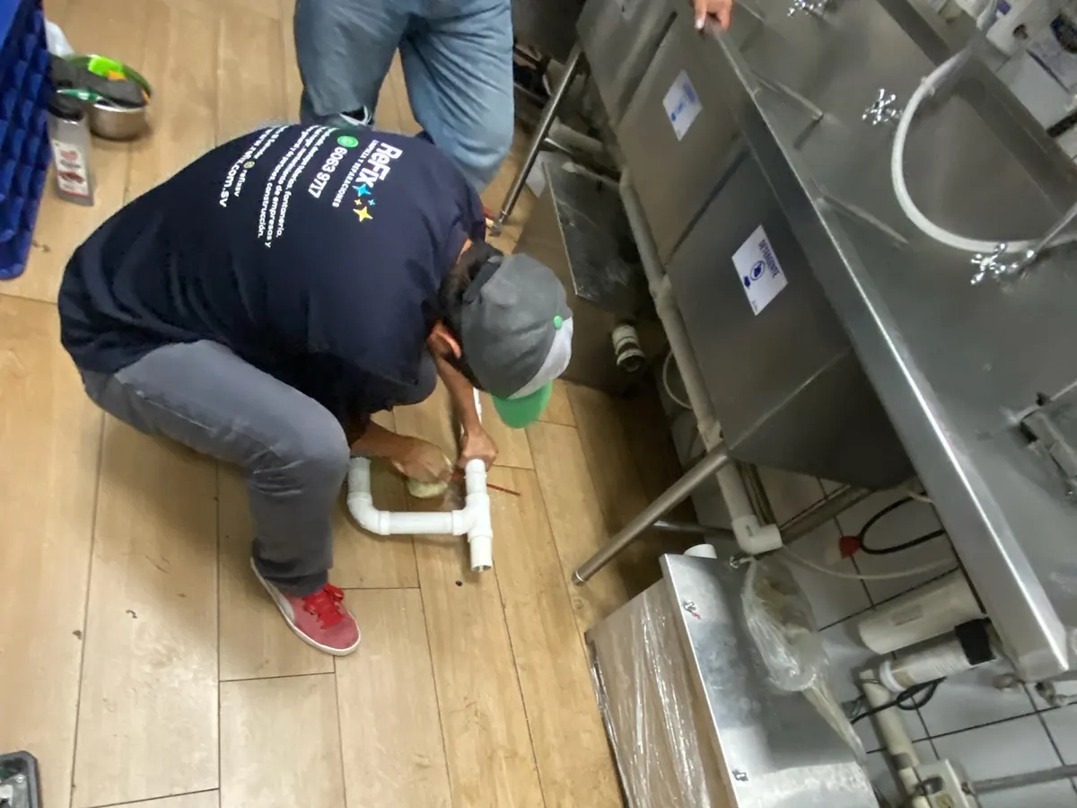 Técnico de ReFix instalando tubería de PVC en la cocina de un restaurante