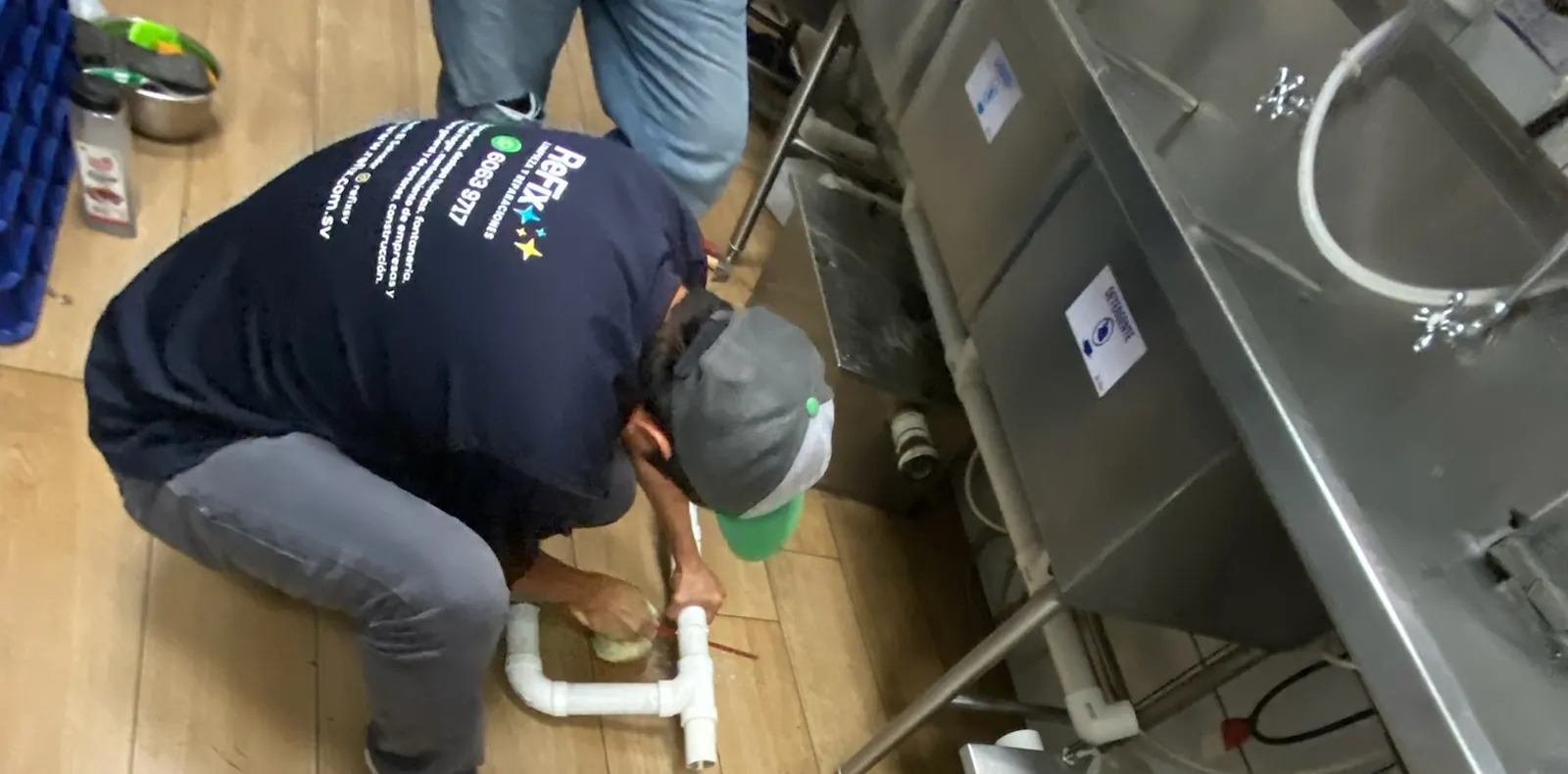 Técnico de ReFix instalando tubería de PVC en la cocina de un restaurante