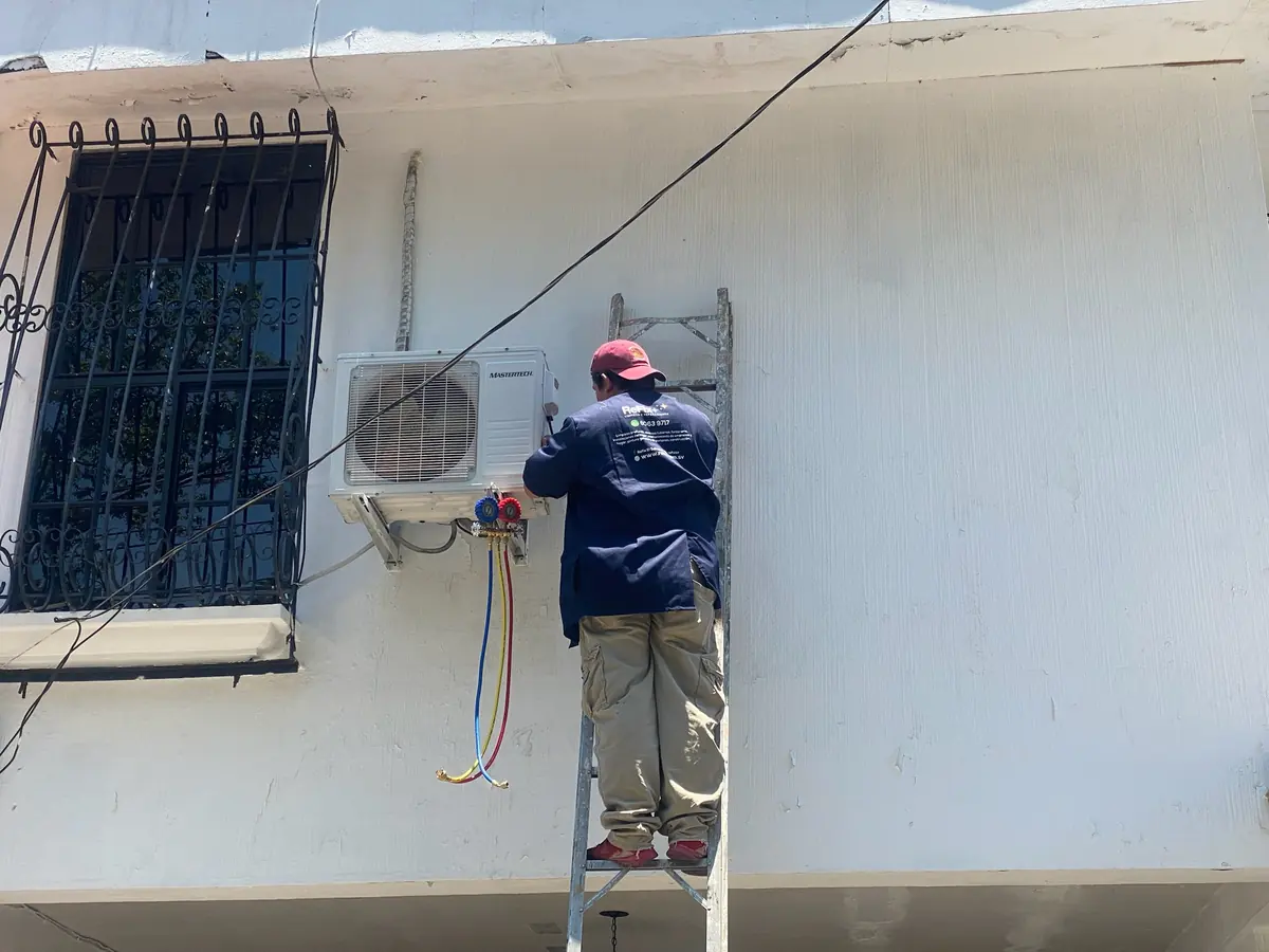 Técnico de ReFix en escalera instalando la unidad exterior de un aire acondicionado