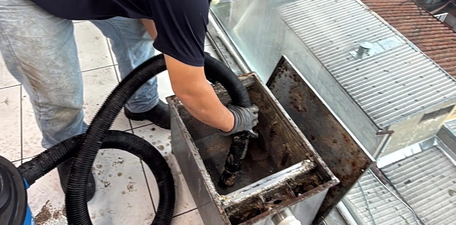 Técnico de ReFix limpiando una trampa de grasa con manguera de succión