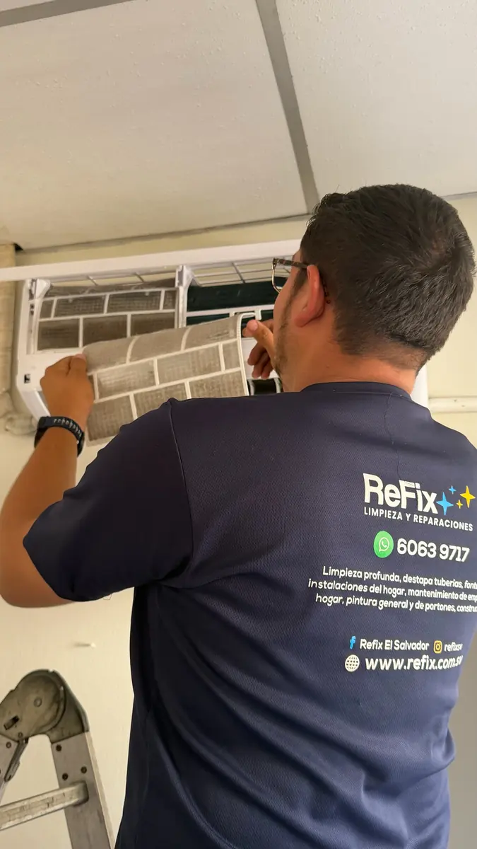 Técnico de ReFix, con la camisa de la empresa, trabajando en la unidad interior de un aire acondicionado