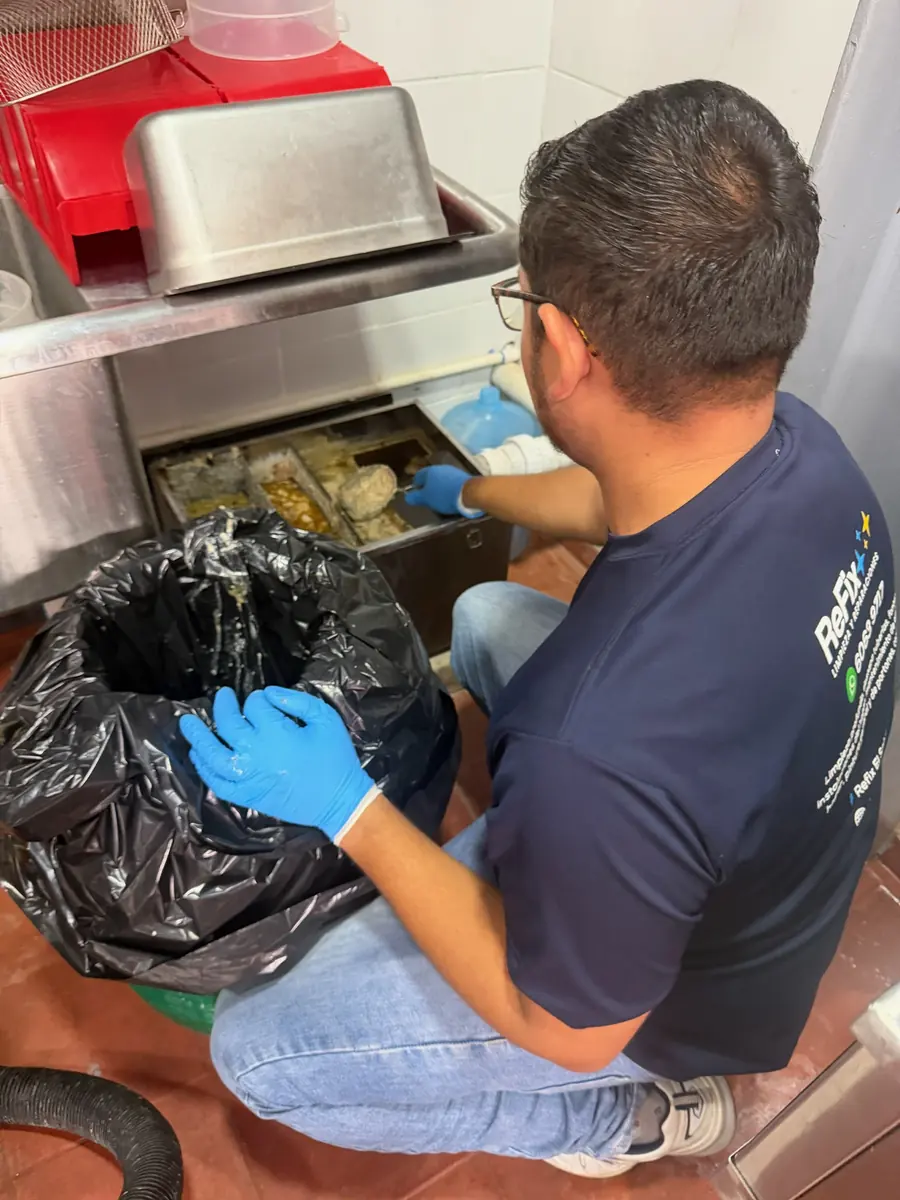Técnico de ReFix limpiando la trampa de grasa de la cocina de un restaurante